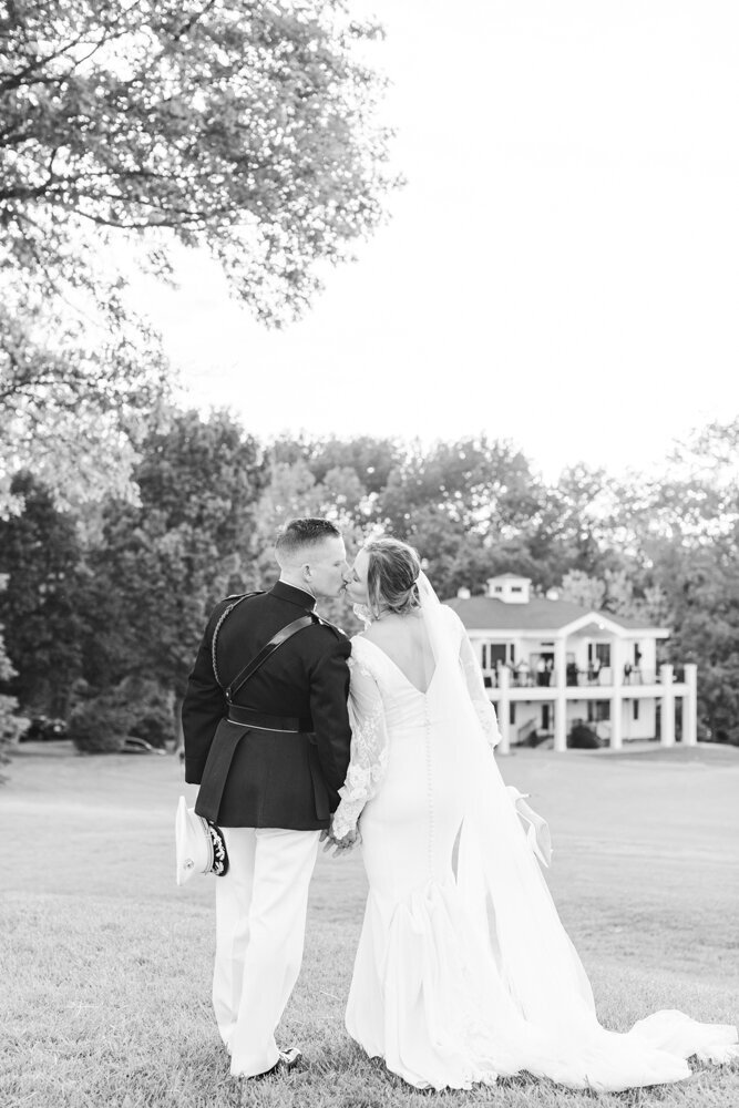 bride and groom kissing with wedding venue in the background