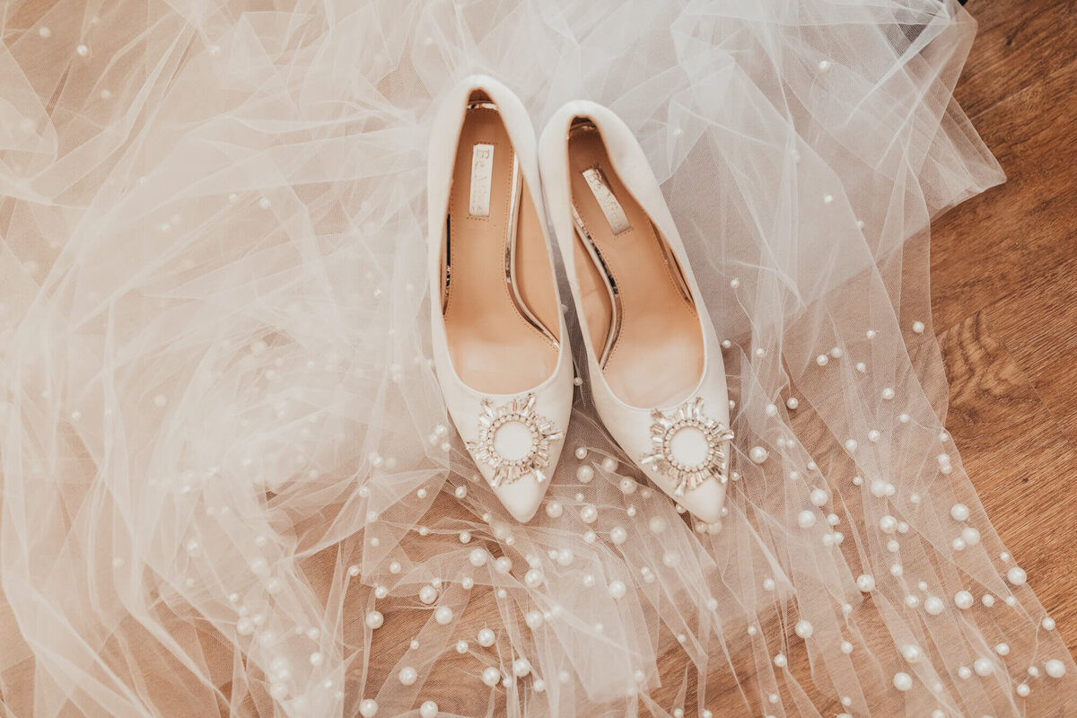 brides shoes and veil sit on floor for detail captures by ally's photography weddings.