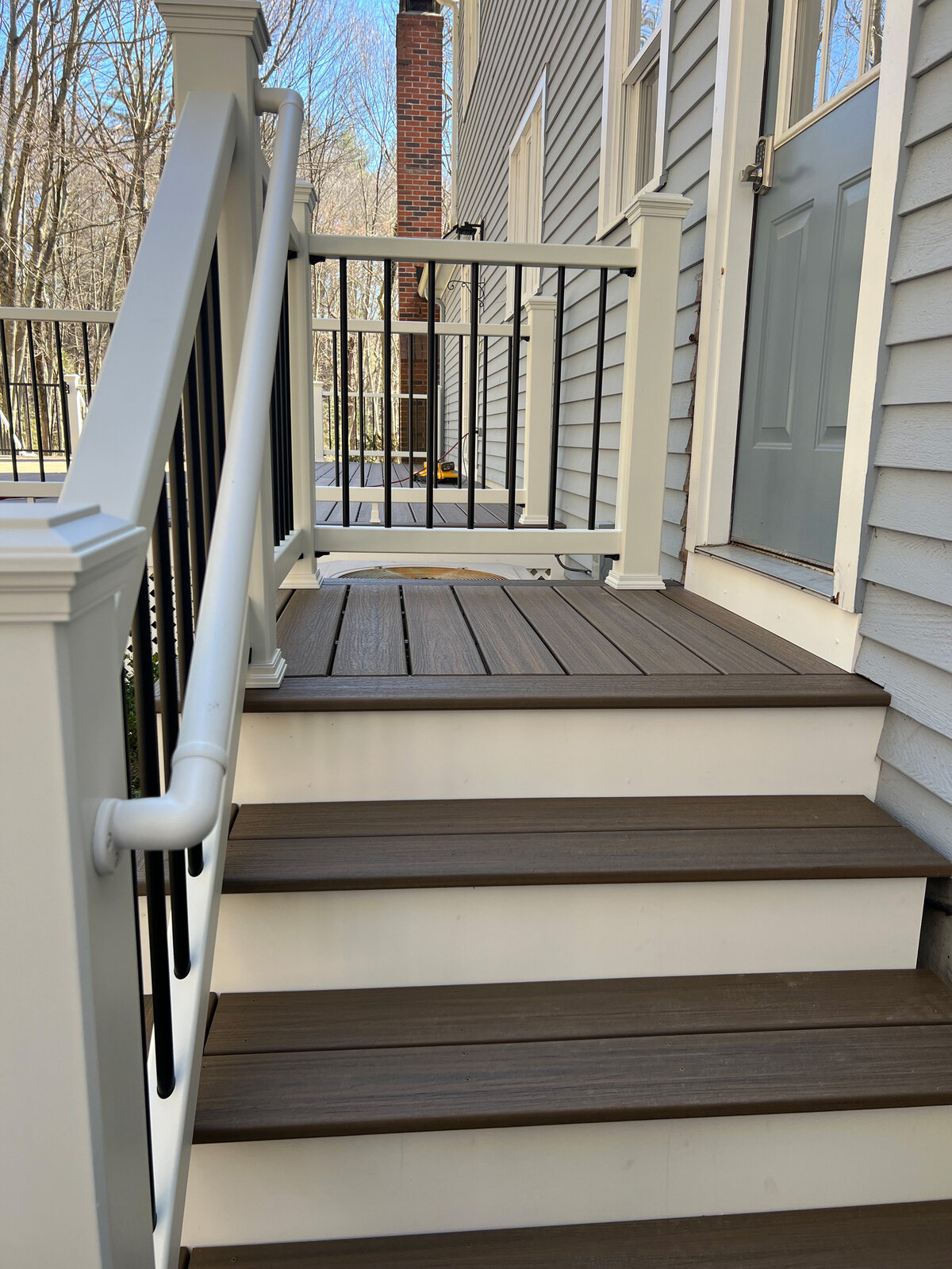 A set of stairs out of dark composite and white PVC railings