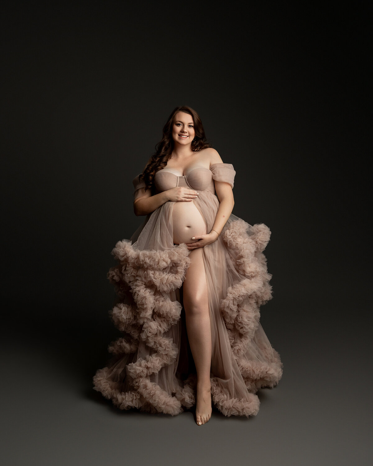 Posed gracefully, her hands gently resting on her belly, capturing a serene and elegant moment. Captured by Inland Empire photographer Kaitlyn Dawn Photography.