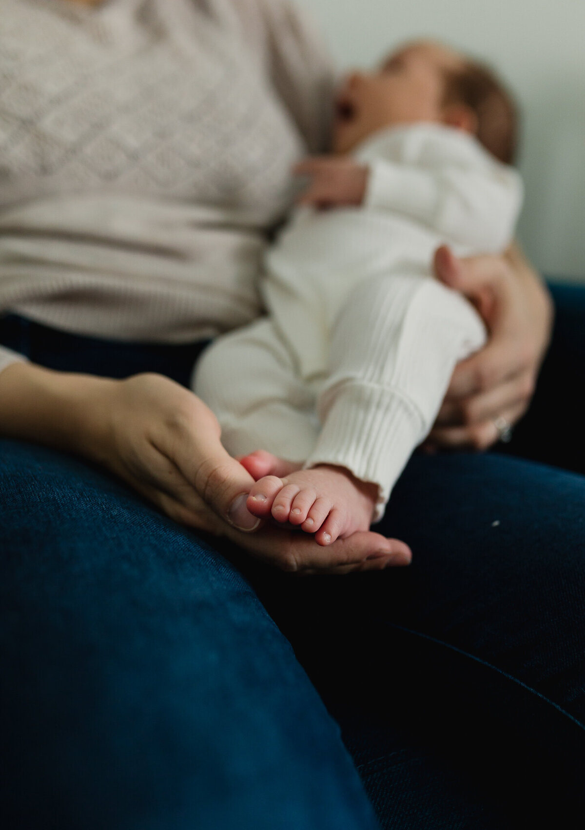 Infant photographer capturing a newborn baby being held in moms arms.