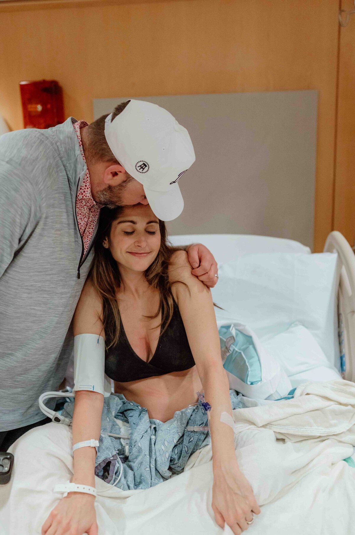husband kissing wife's head during an intimate moment after birth