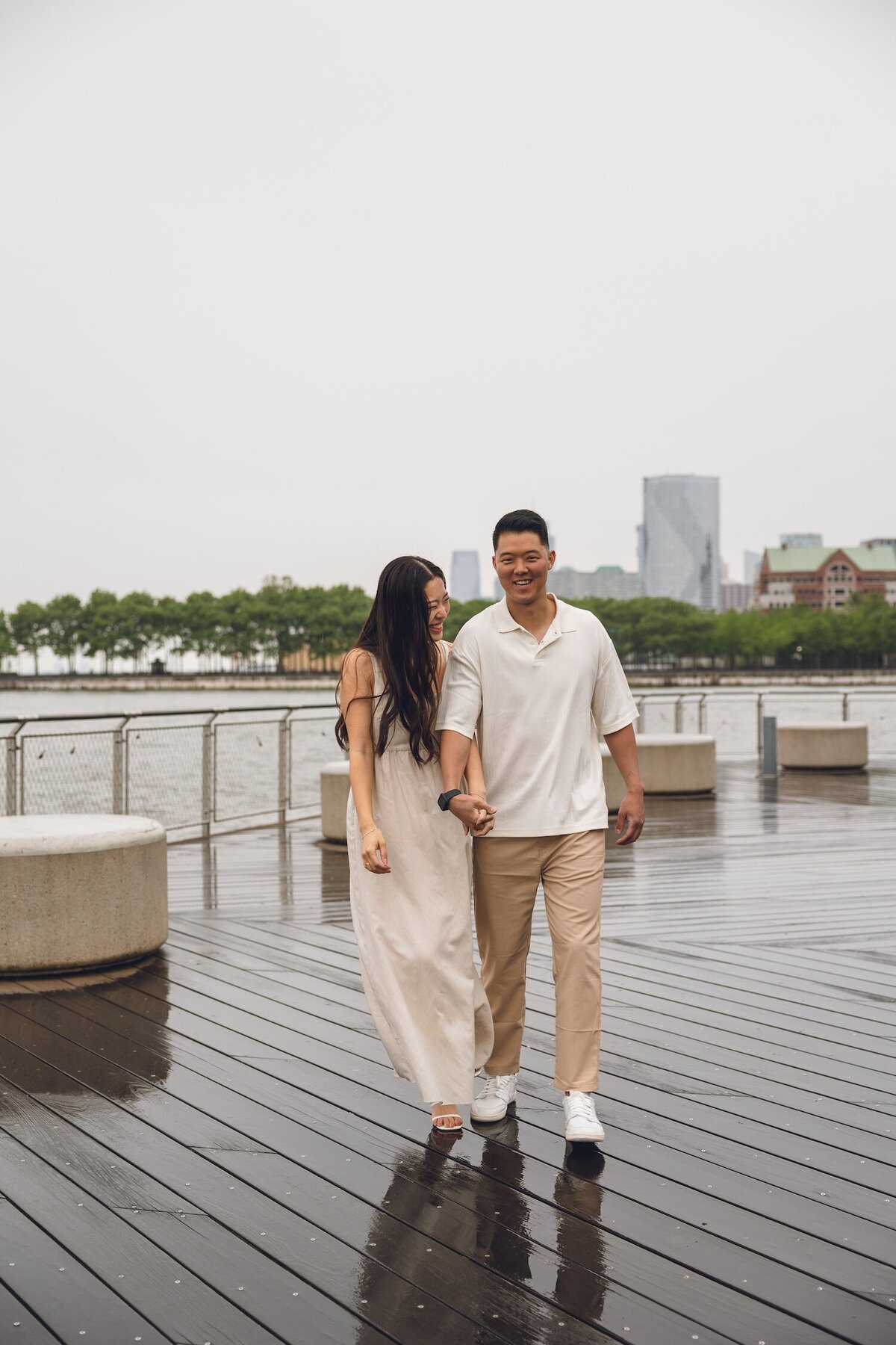 couple walking on rainy waterfront boardwalk