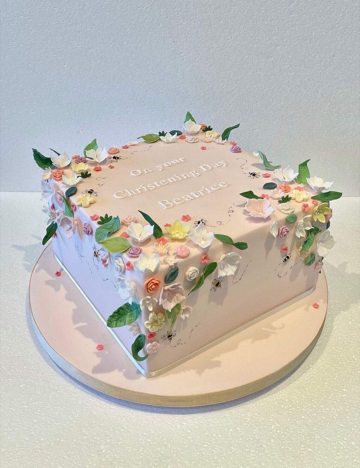 A square christening cake with lots of mini sugar flowers all over