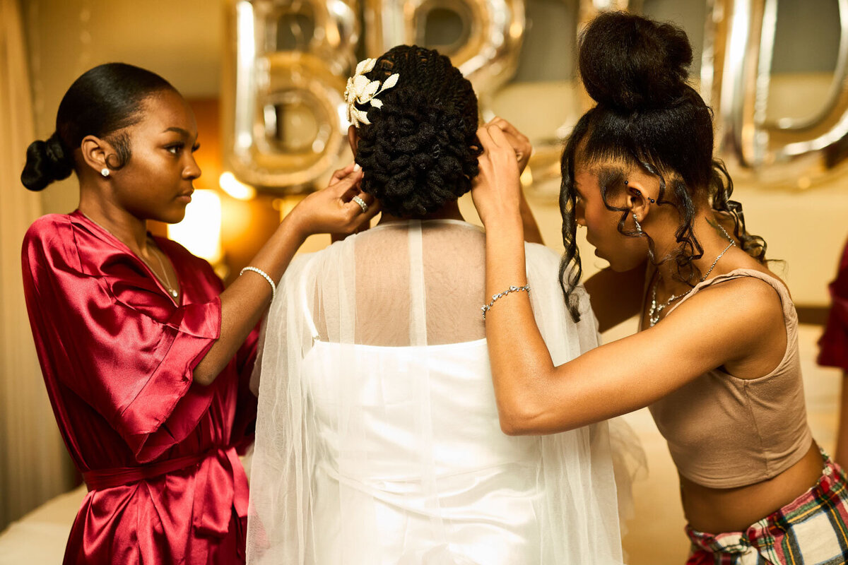 Bridesmaids helping bride fix her hair