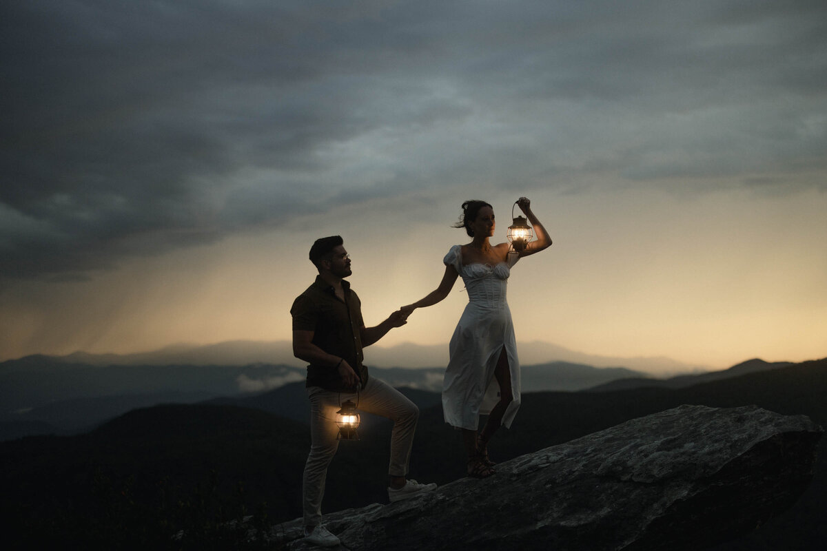 bride and groom standing on cliff with mountains in background