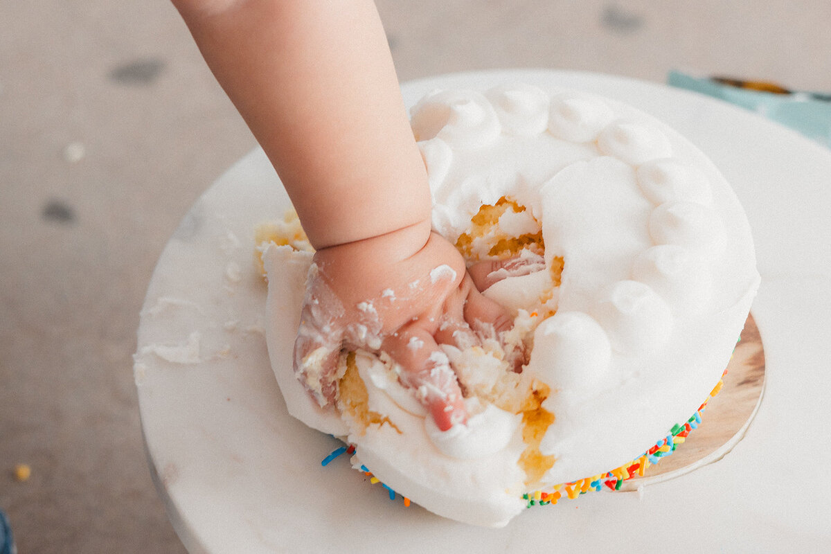 A little hand reaches into cake.