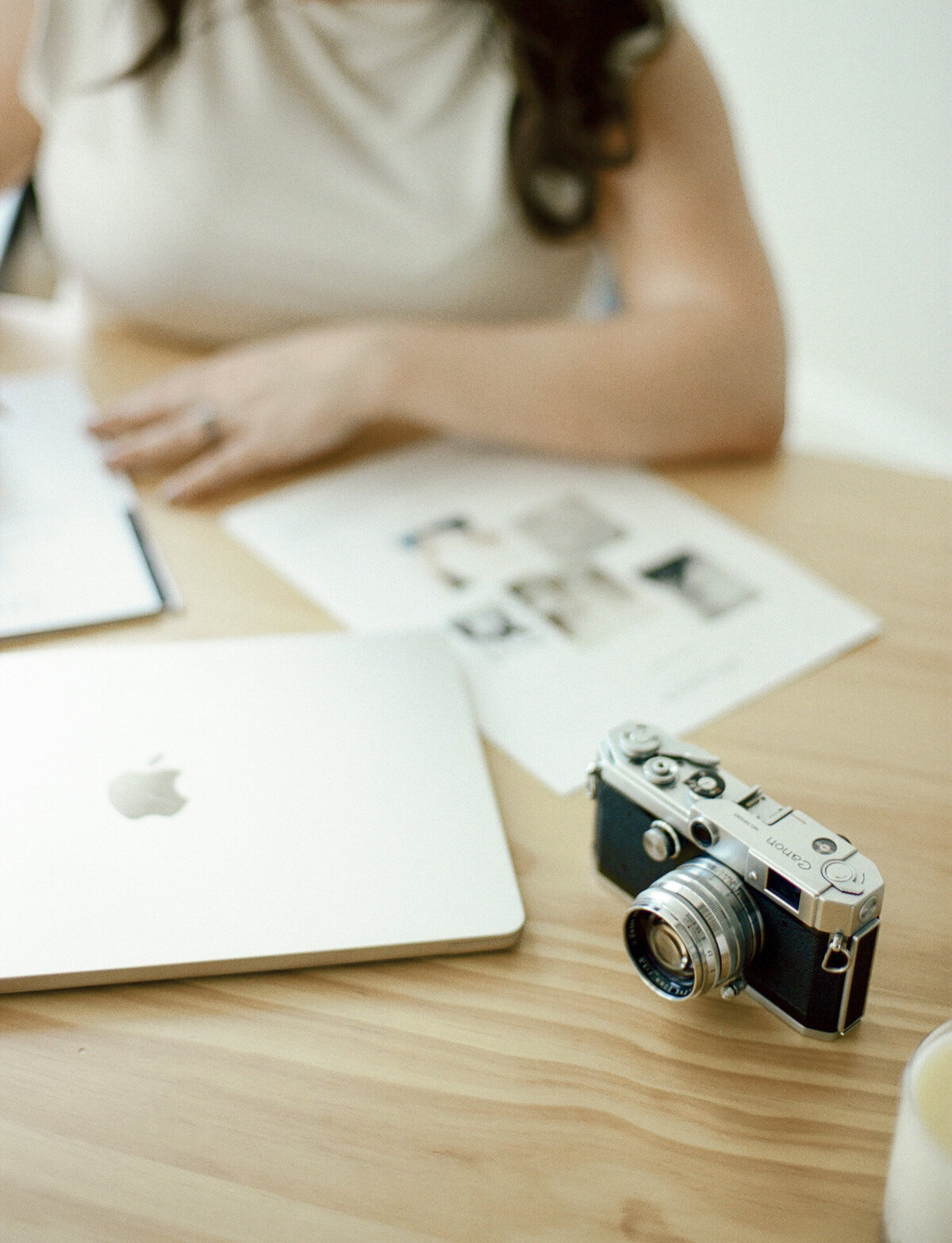 wood desk with vintage camera, champagne color macbook, woman working