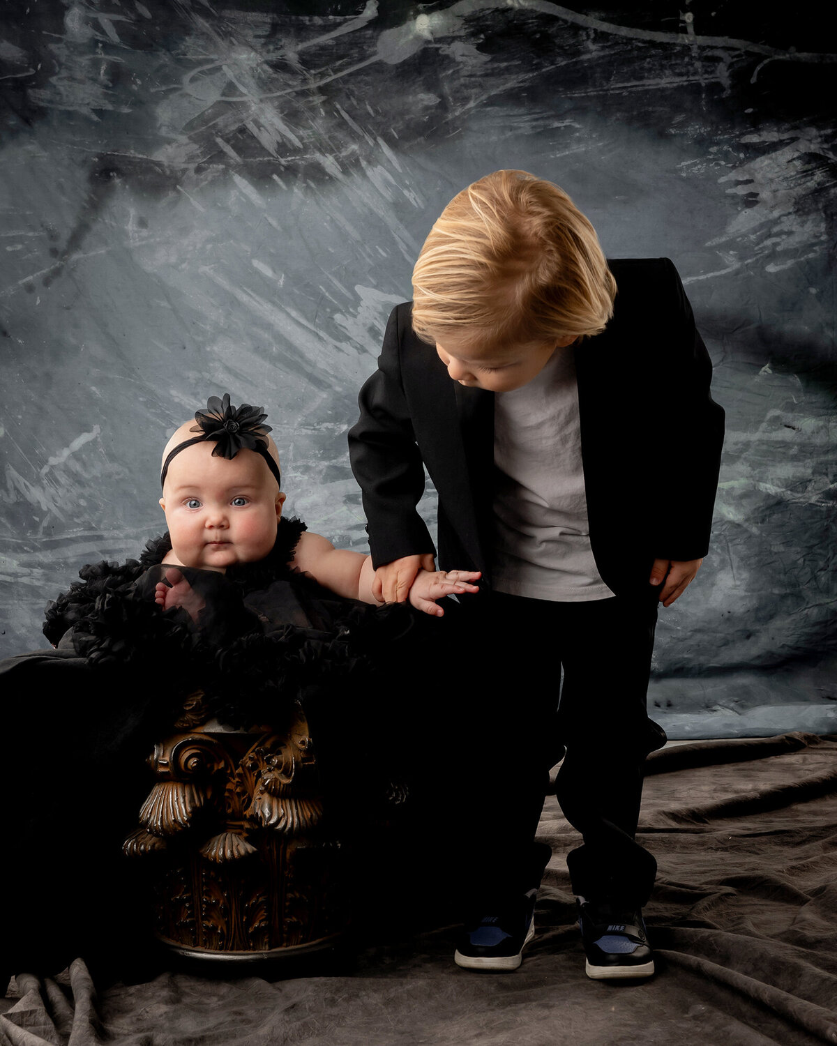 Big brother looks down at his little sister sitting