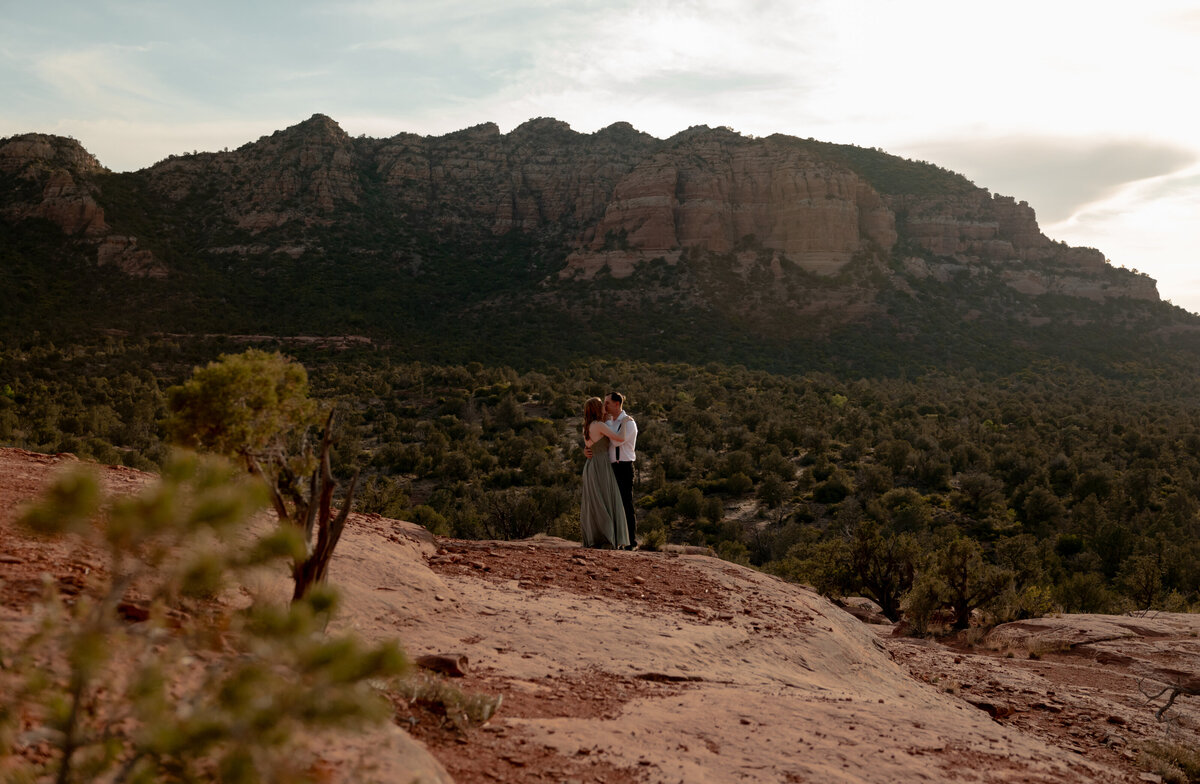 Couple standing against red rock backdrop during Sedona engagement session