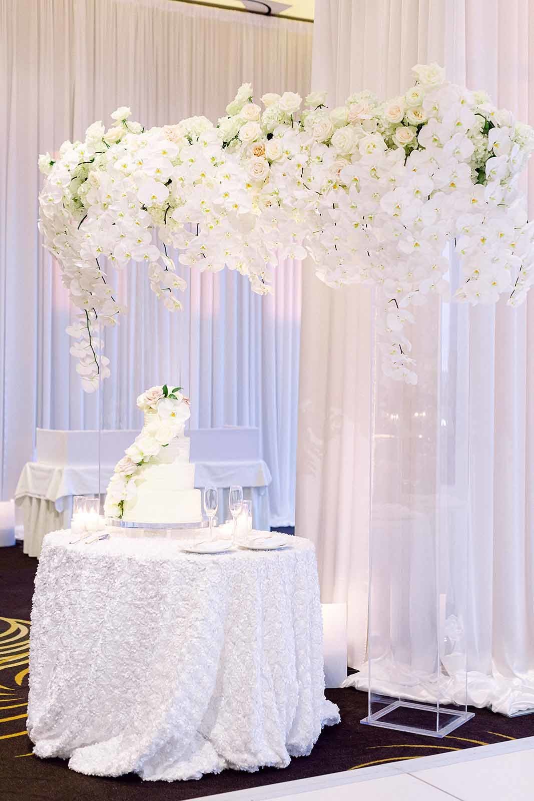 cake table with white orchid arbor as background