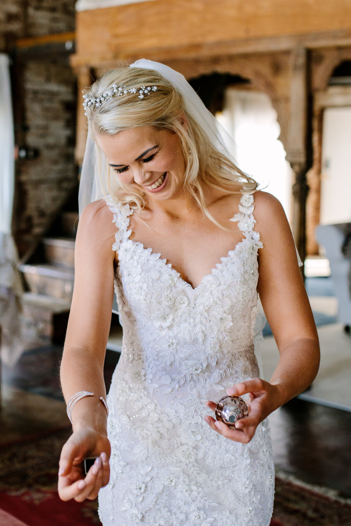 Bride giggles as she sprays perfume on herself before getting married. 
