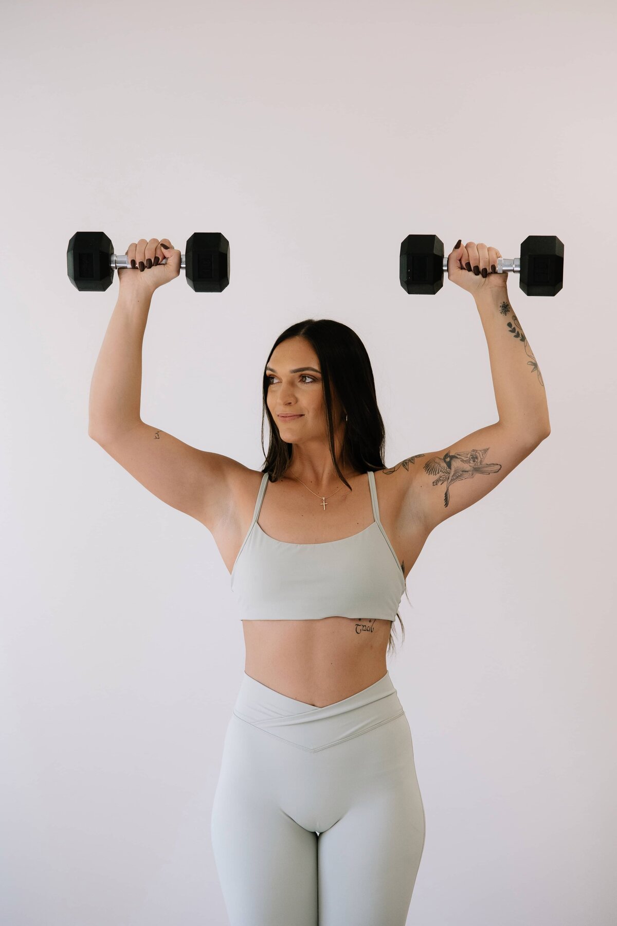 A fitness coach does shoulder presses with weights during her branding session in Northern, Colorado.