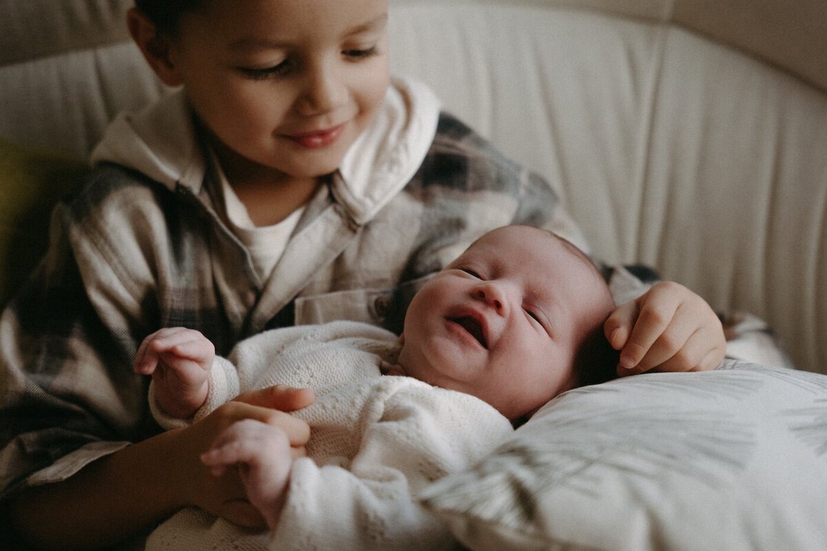 Le grand frère tient sa petite sœur dans ses bras et lui sourit tendrement. Capturé par Kamescop, vidéaste et photographe naissance.