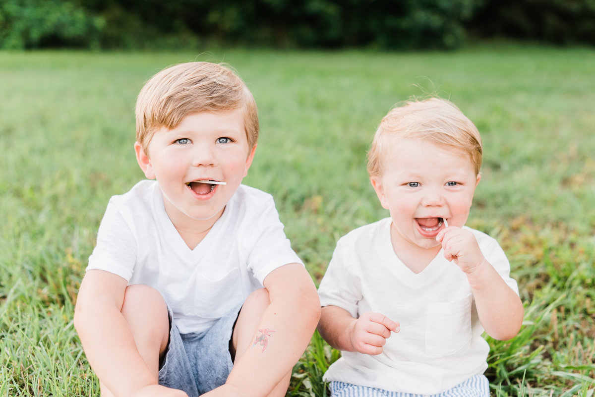 Brothers eat lollipops and smile during their family photo session in Raleigh NC. Photographed by Raleigh NC family photographer A.J. Dunlap Photography.