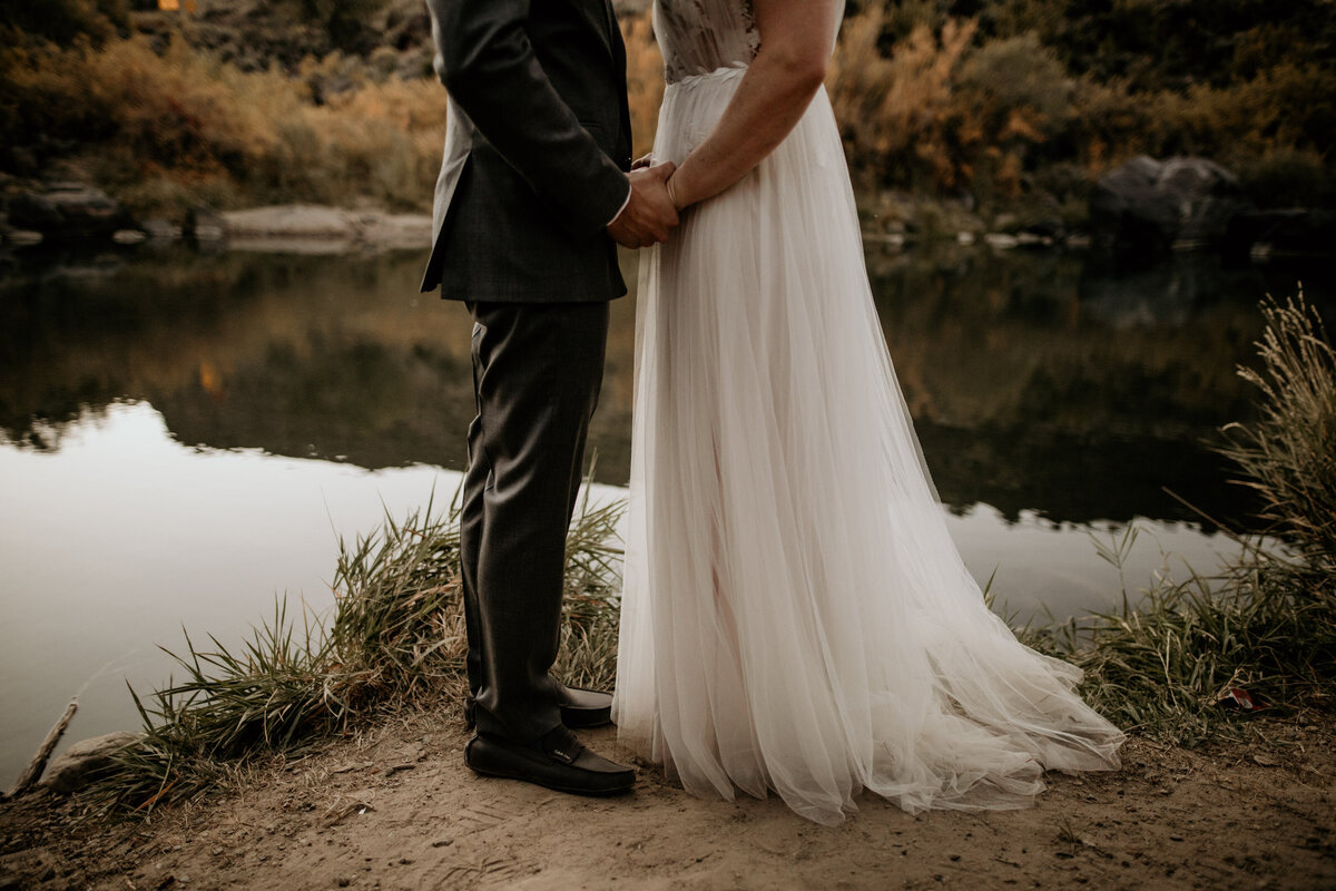 bride and grooms legs standing next to a river