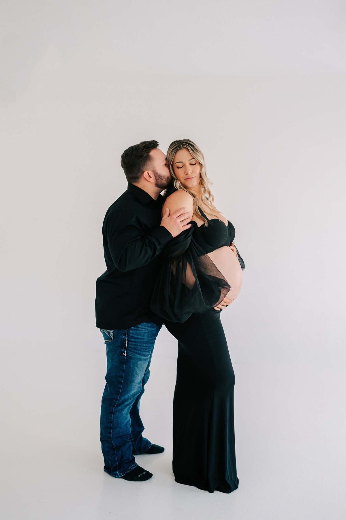pregnant couple in black outfit cuddling enjoying their maternity photography in Springfield MO