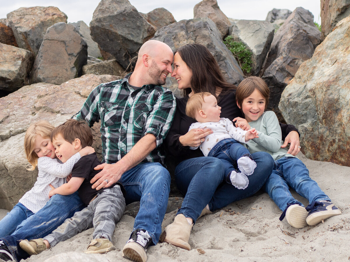 a family of 5 is sitting together at Edmonds beach for a family photo session taken by Seattle birth photographer, Becky Langseth