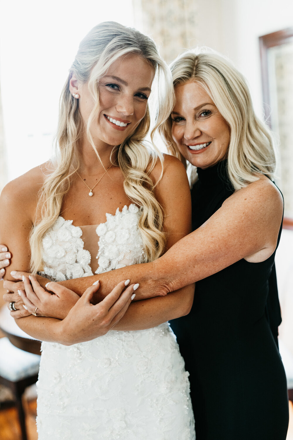Mother of the bride in a black dress hugging the bride at a sophisticated black, white, and gold wedding at Ashford Acres Inn, Cynthiana, KY