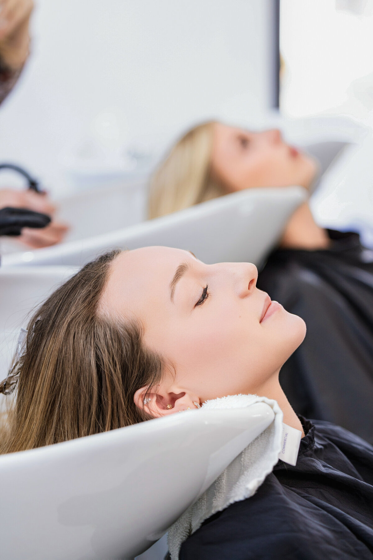 A stylist and her client share a joyful moment during a hair appointment. This warm, engaging branding shot is perfect for showcasing a salon’s welcoming atmosphere and client-first experience.