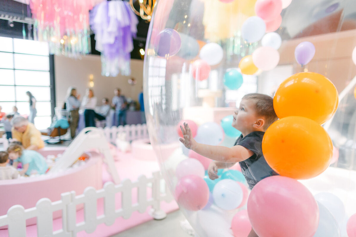Colorful bounce house at a children’s birthday party venue, surrounded by vibrant balloons, playful decorations, and festive table settings, creating a fun and lively atmosphere