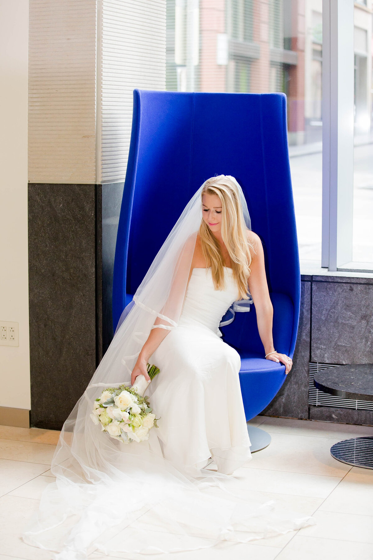 bride posing in the blue chair in the fairmont hotel lobby in pittsburgh