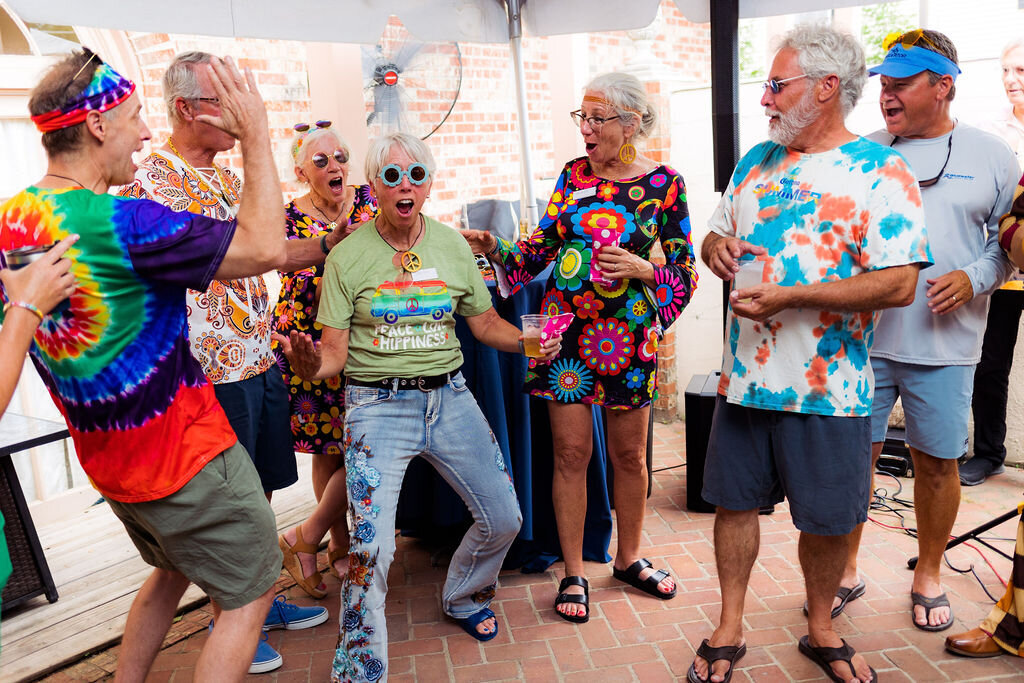 A group of people in decades-inspired clothing all have fun.