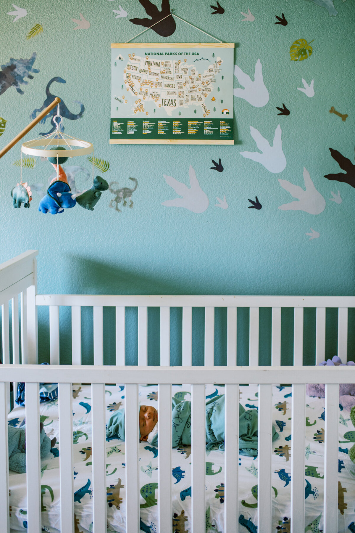 newborn baby sleeps in his white crib in his green nursery