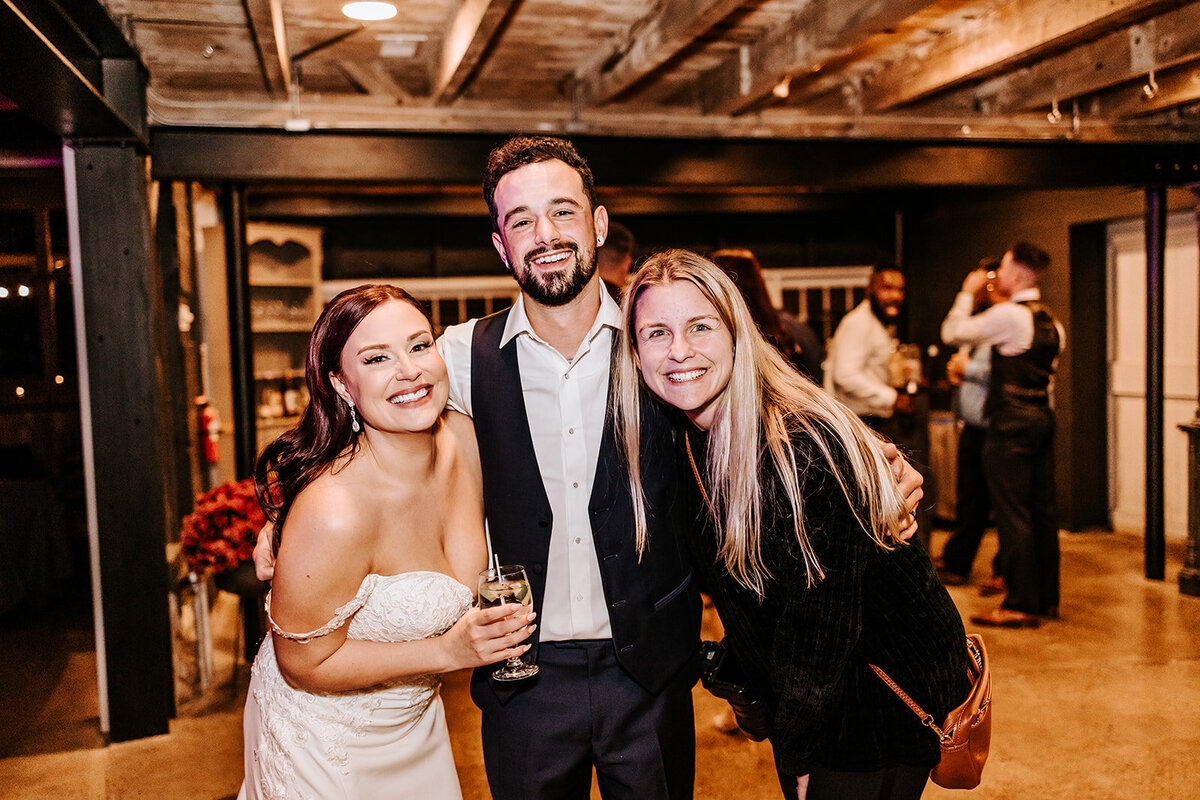 Bride and Groom smiling with Wedding Photographer in and old stone barn