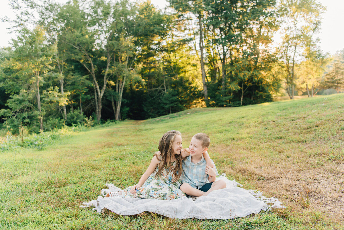 Brother and sister sitting on blanket in field