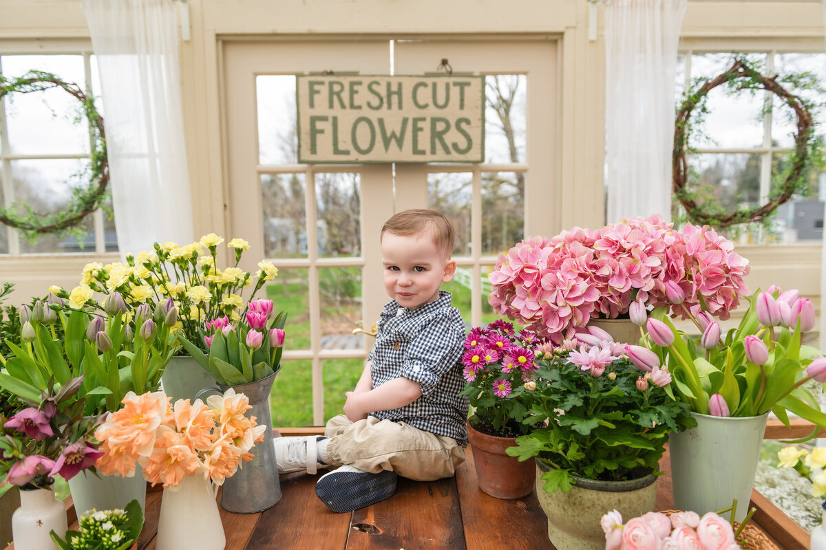 Spring greenhouse portrait of a child surrounded by flowers in a All Who Wander Flower Farm in Dundas Ontario floral market setup