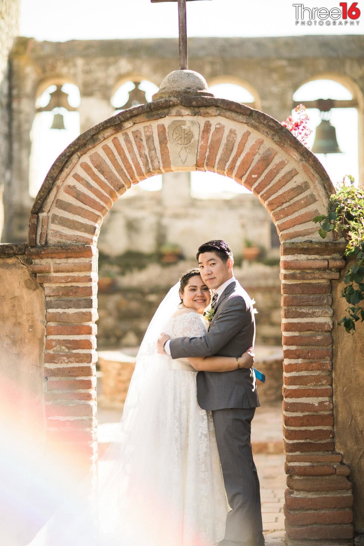 Bride and Groom pose for the photographer under a brick archway
