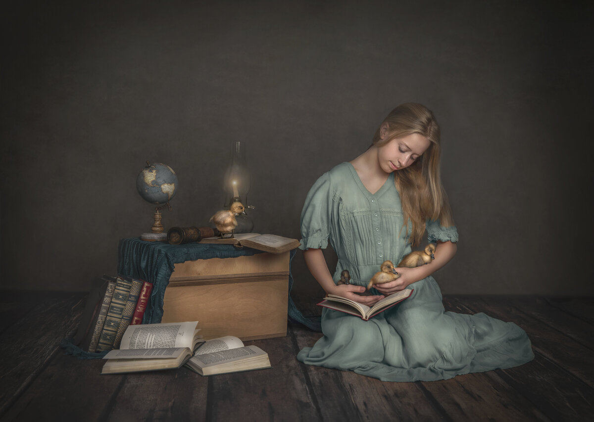 A young girl dressed in light blue holds three out of the four ducks while reading a book. Photo taken by Sonia Gourlie In Ottawa.