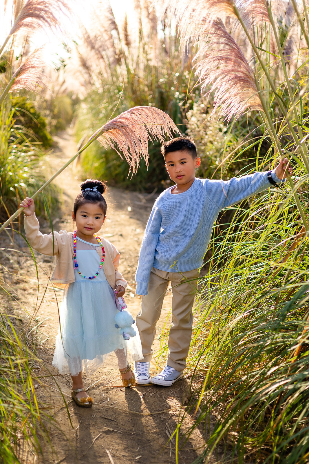 Brother and sister holding tall grass stems on trail – Bay Area Family Portfolio captured by Ellobelle Photography
