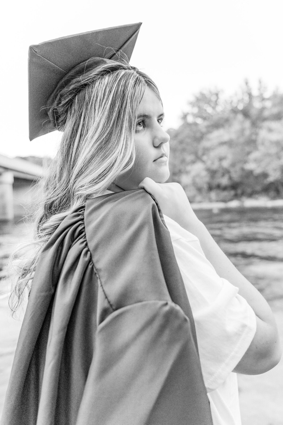 Black and white senior portrait of a graduate holding her gown near the water — Ohiopyle senior session by Bree Stewart of Lens Love Photography.