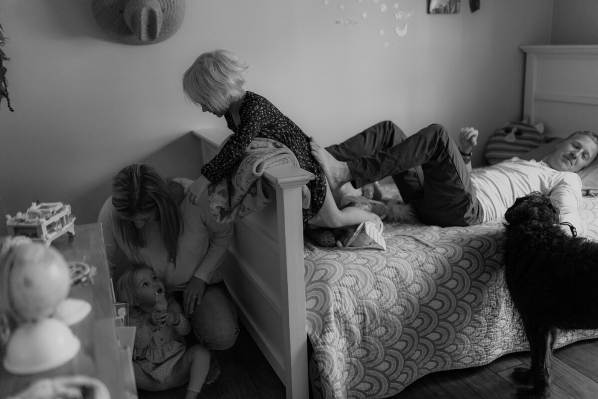 black and white image family playing on bed