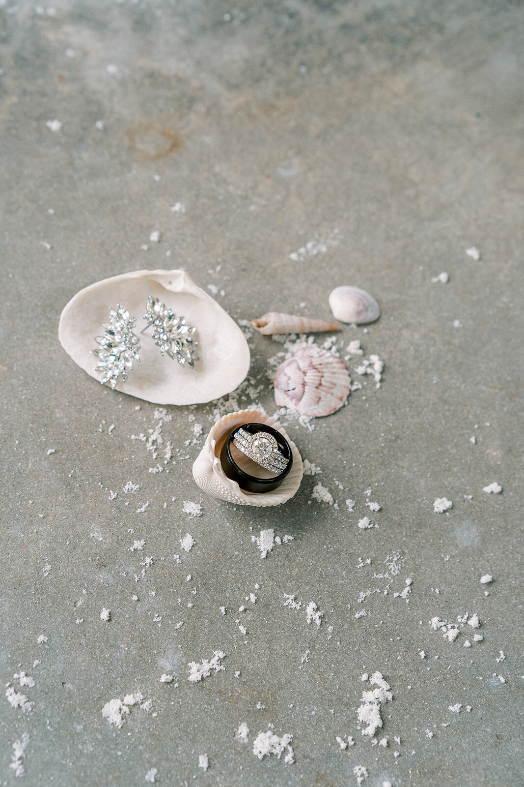 wedding jewelry sitting on seashells in the sand