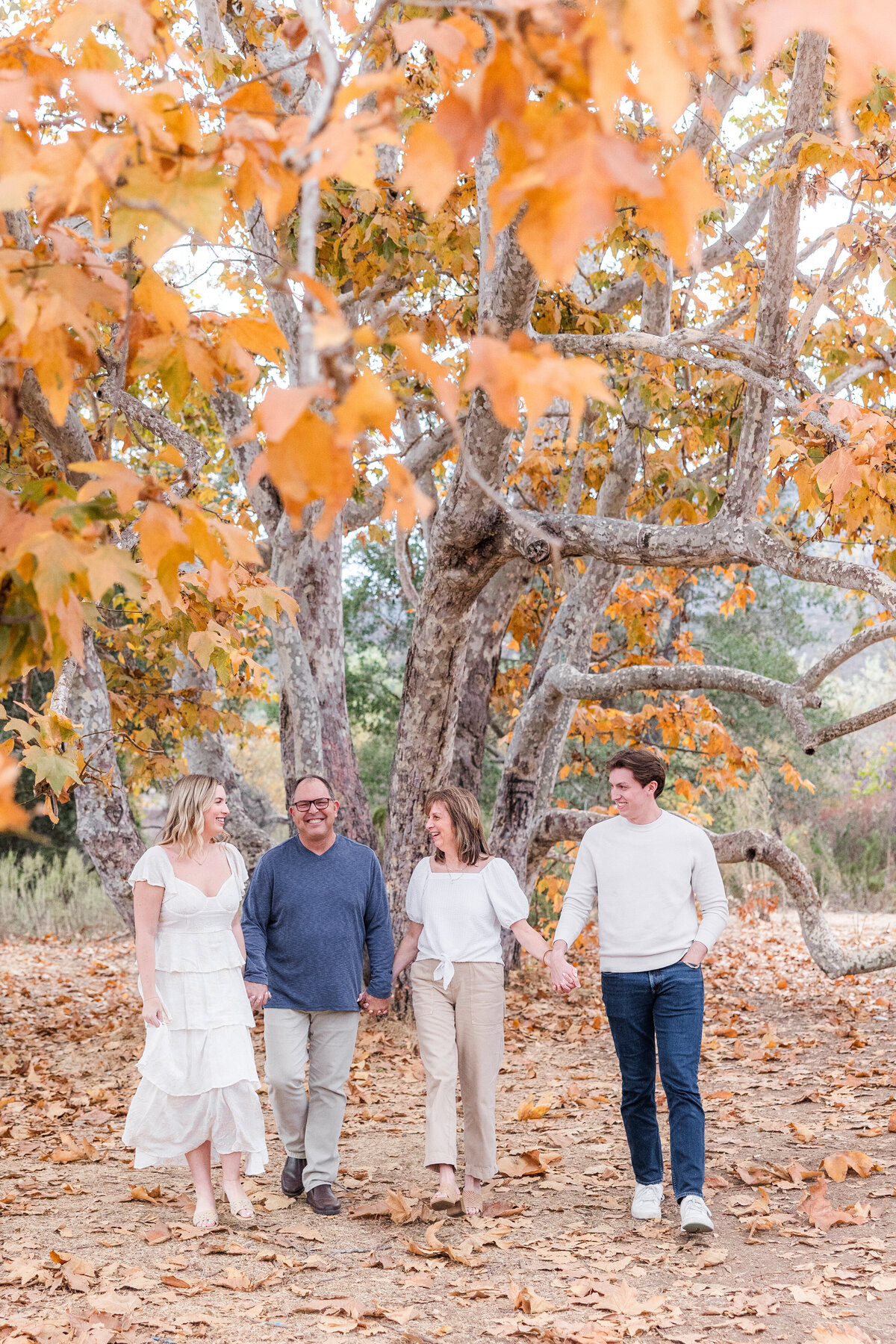 parents with adult children under tree with fall leaves