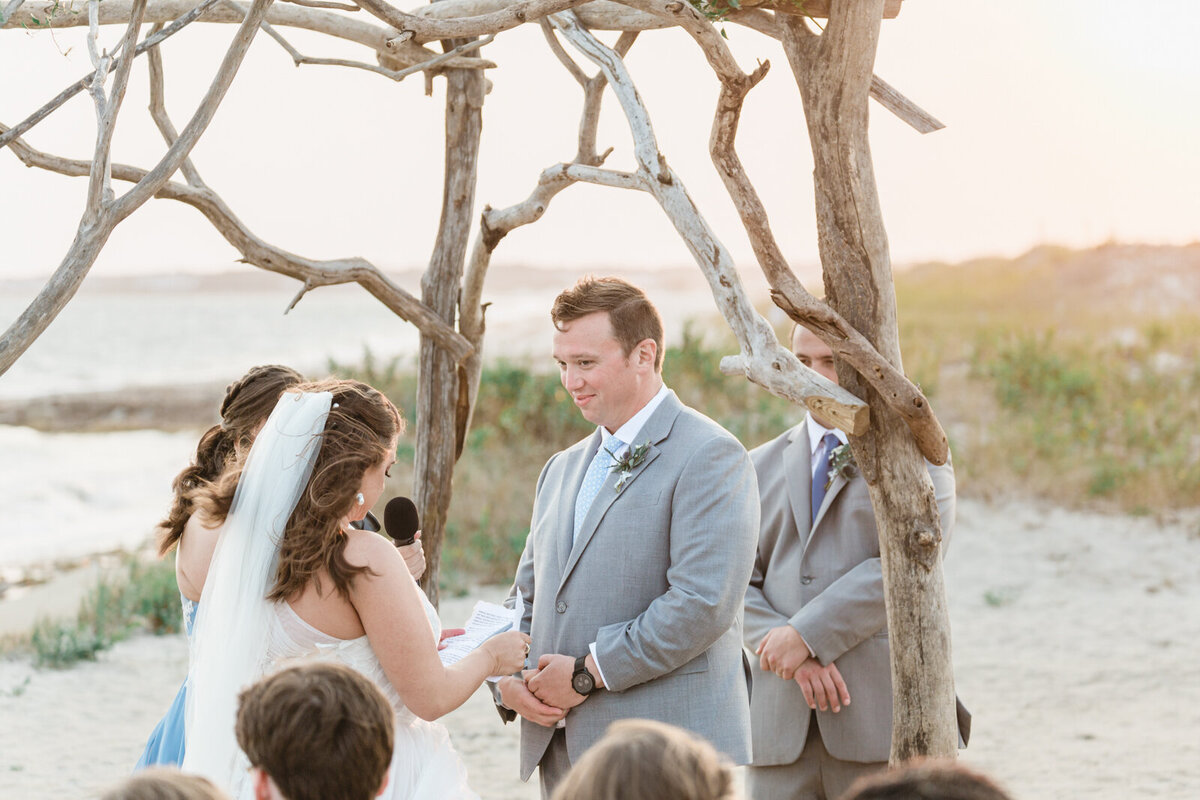 A bride says her vows surrounded by a drift wood  chuppah