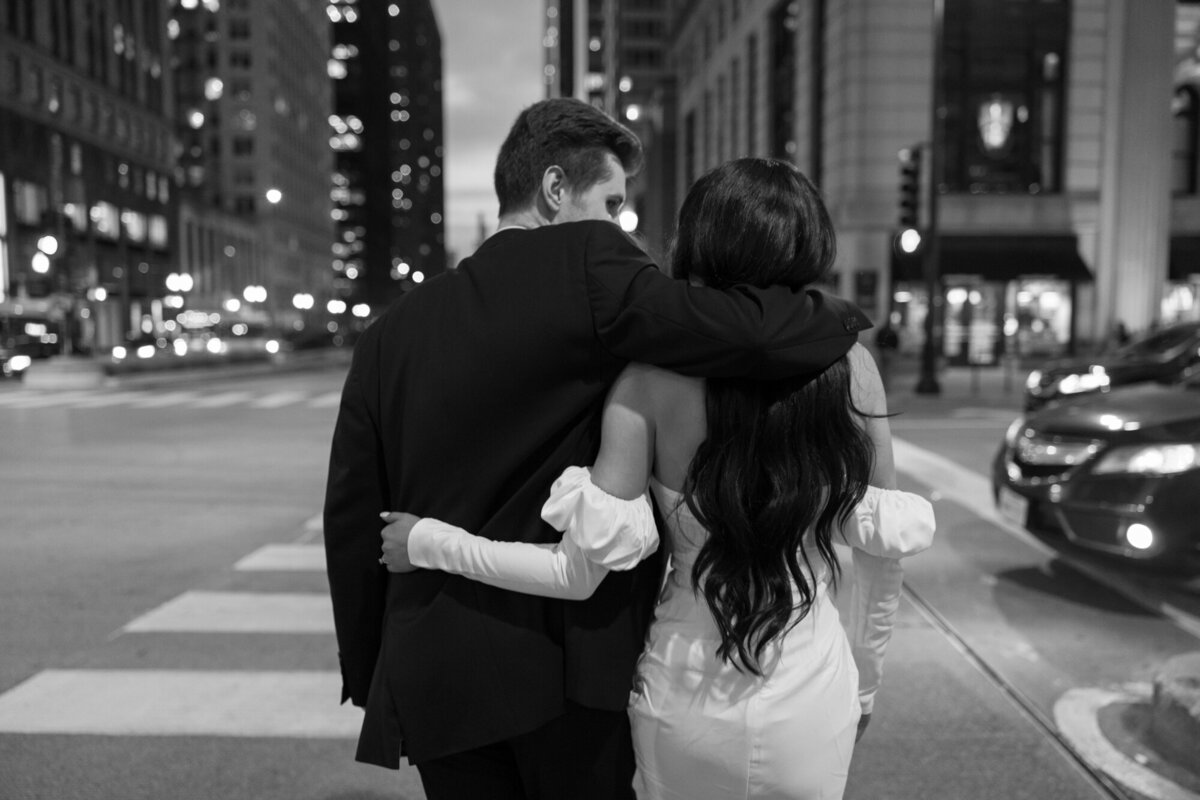 A couple embraces at dusk along Michigan Avenue and the Chicago River, with the city lights creating a romantic and timeless backdrop.