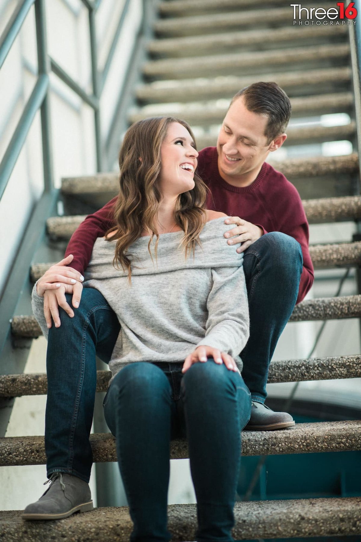 Bride to be looks back at her fiance while sitting together on some stairs