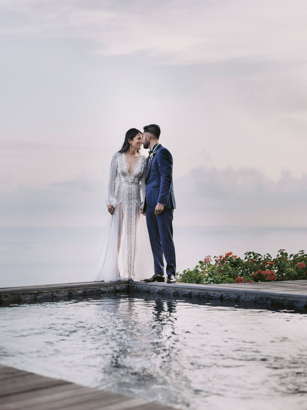 The bride and groom are romantically facing each other at the edge of a pool in Khayangan Estate, Indonesia. Image by Jenny Fu Studio