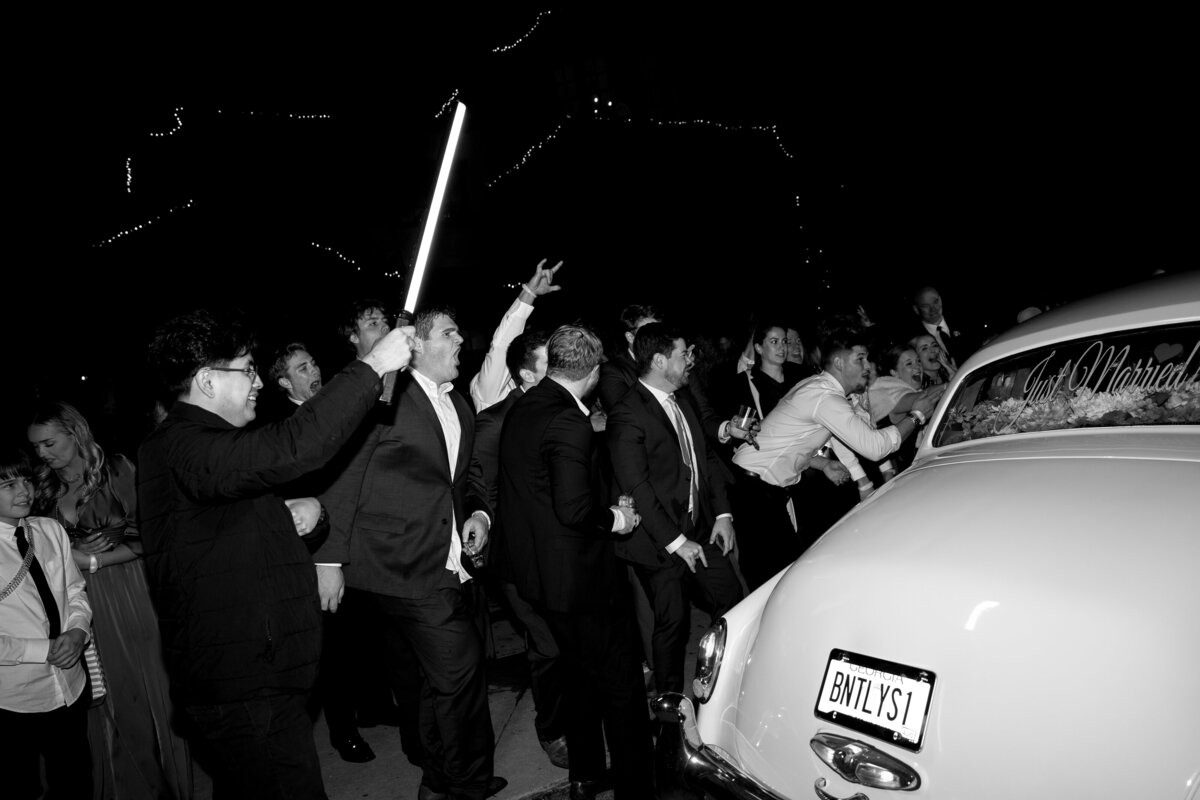 Reception guests cheering for the bride and groom as they pull away in their getaway car outside of Montaluce Winery in Georgia.