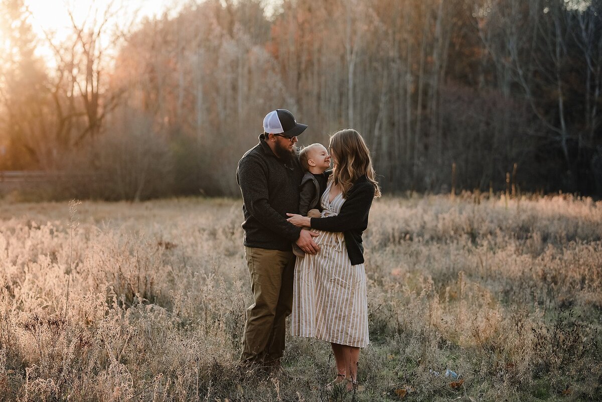 pregnancy pic with husband and toddler in field at sunrise