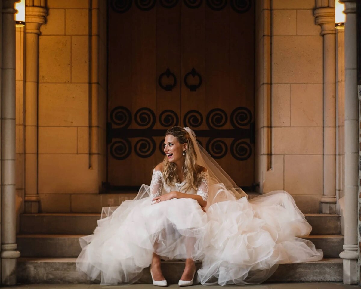 A bride sitting on a small staircase laughing