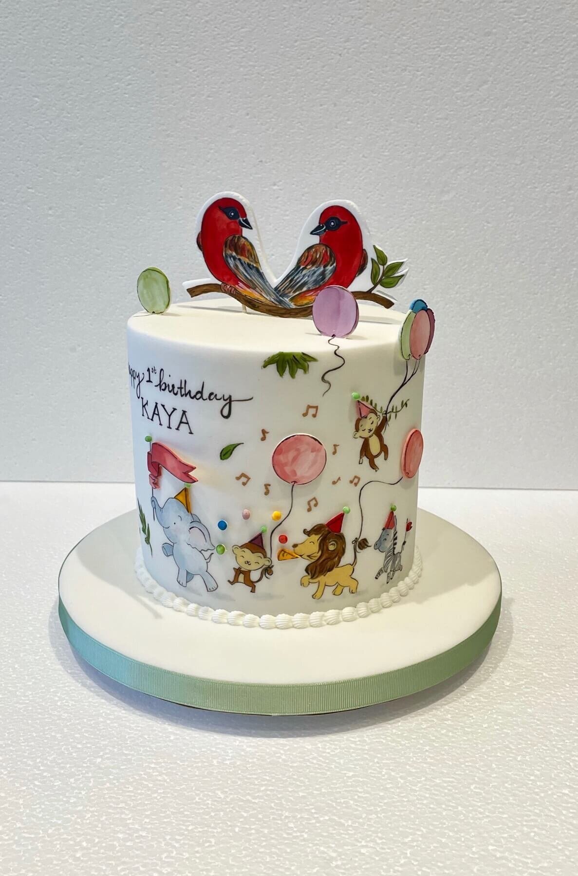 A hand painted birthday cake with animals and balloons