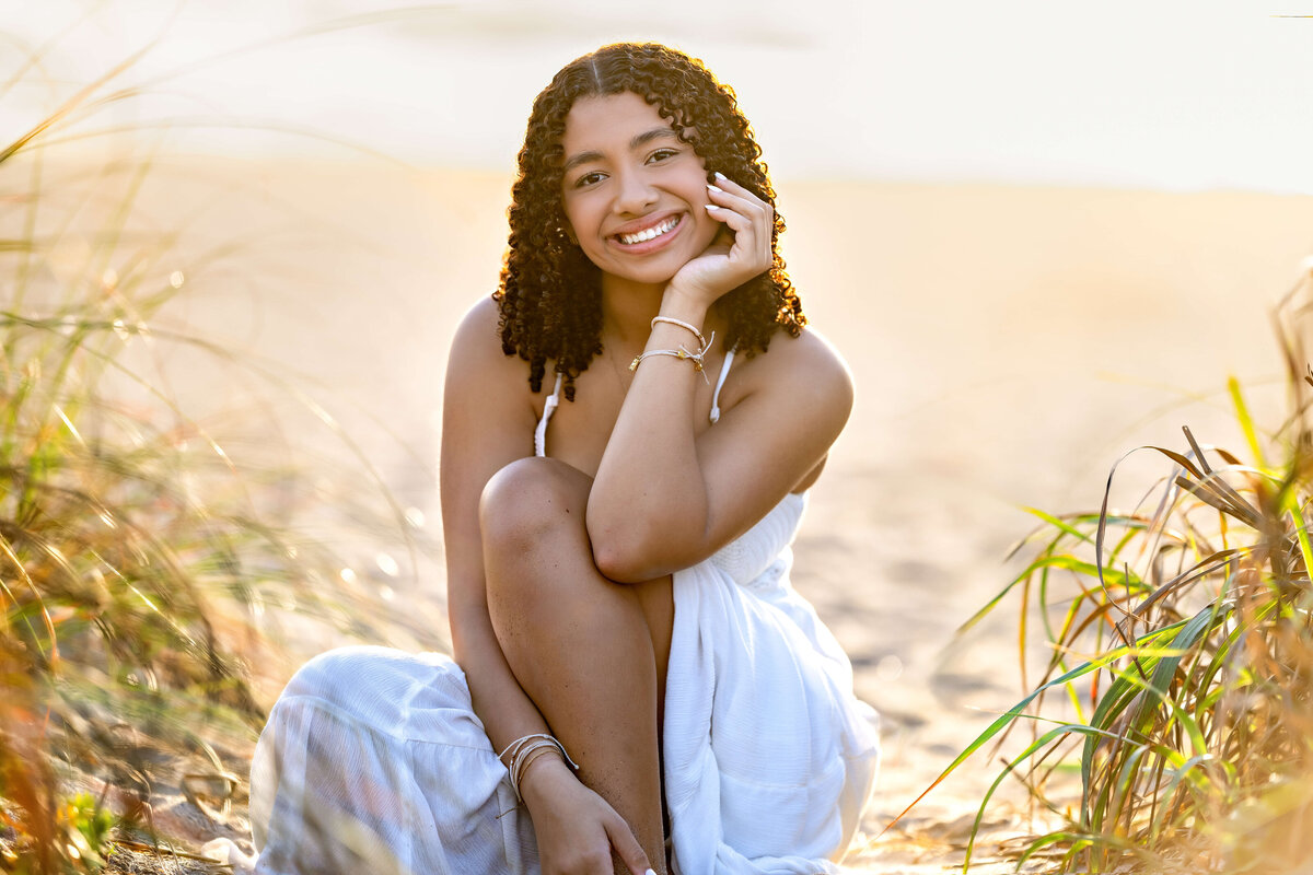 Orlando senior session with a girl standing on the beach, smiling directly at the camera in a soft morning sunrise light.