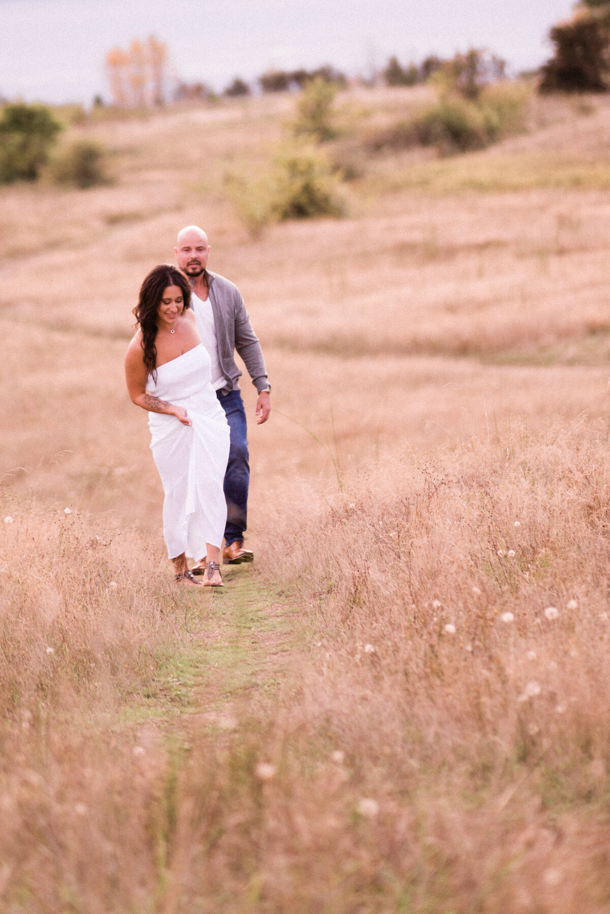 Husband and wife stroll through flowers and tall grasses at the best spot for intimate engagement photos in Seattle
