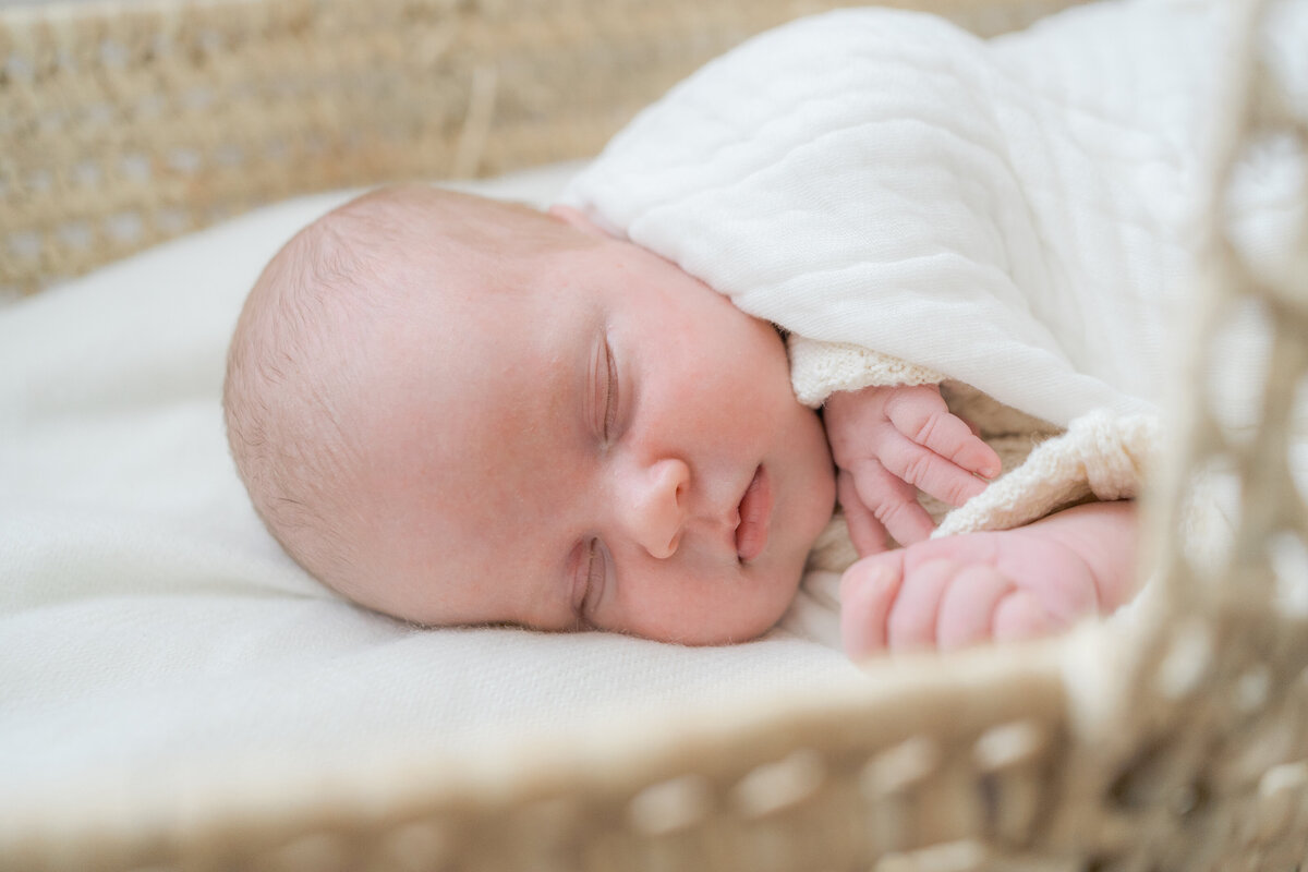 Baby sound asleep in her basket with a white muslin blanket by Oklahoma City Newborn Photographer Courtney Cronin