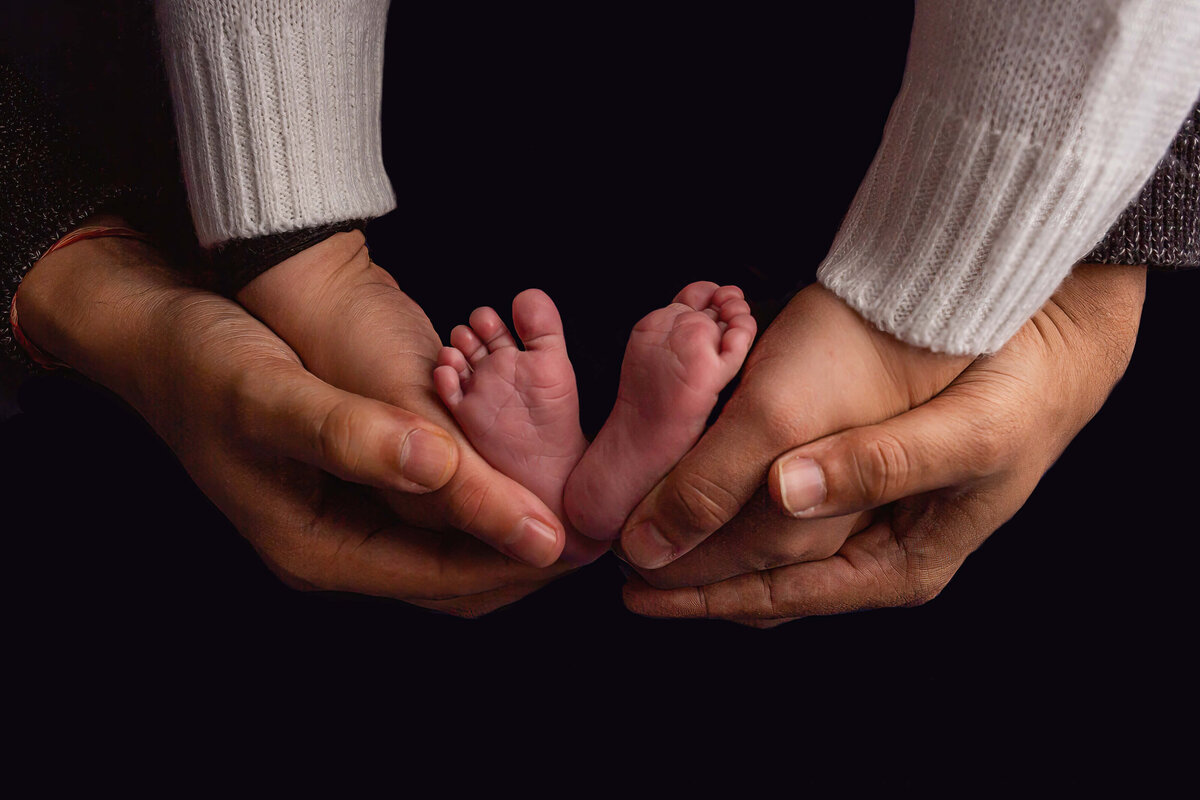 close up of parents hands  cradling newborn baby feet